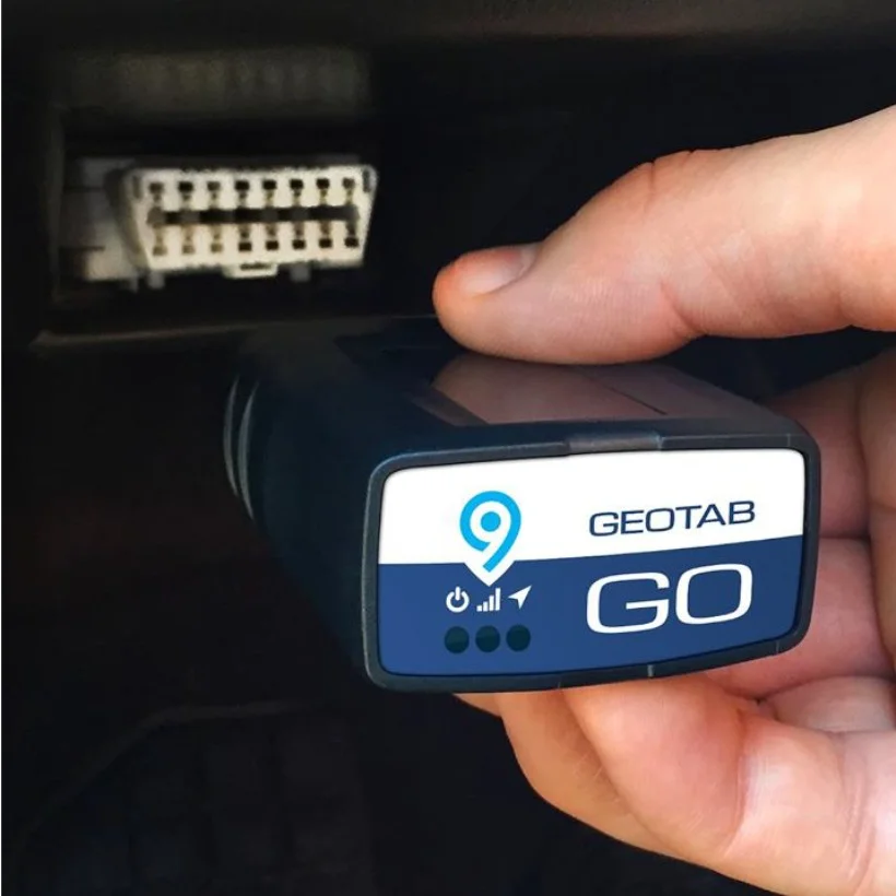 A Geotab GO9 in hand at the vehicle's OBD-II port